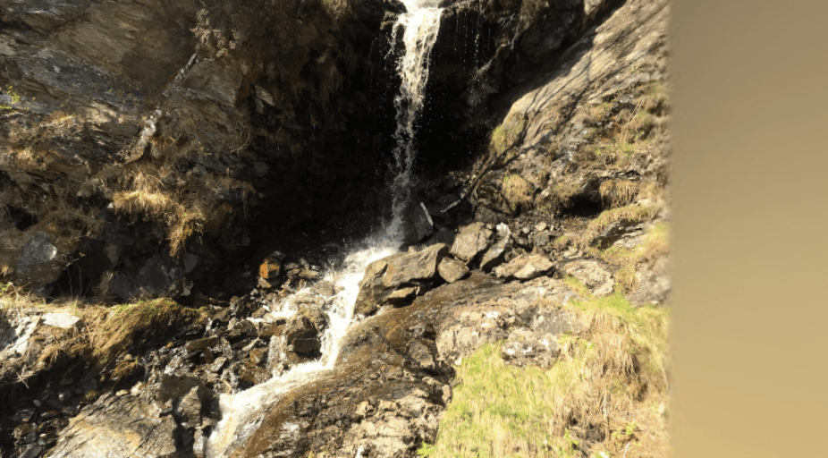 thin waterfall cascading over rocks with hidden cave behind