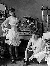 two Victorian era prostitutes in a bedroom wearing undergarments