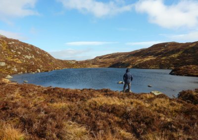 man standing beside a small Scottish lochan.