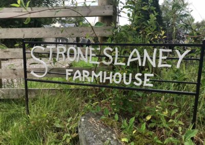 wooden and iron fence with a sign reading "Stroneslaney Farmhouse"