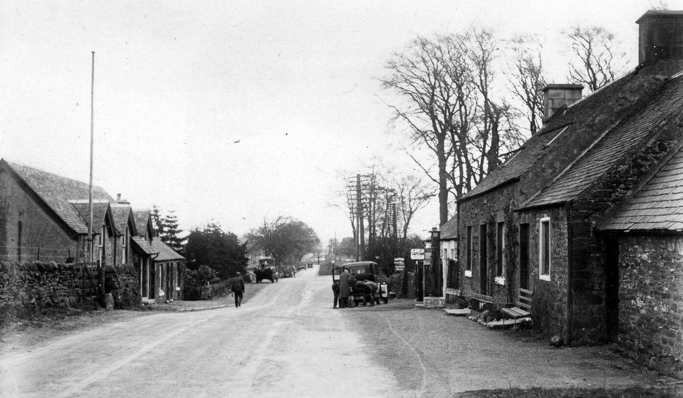 old black and white photo of the main street of a small Scottish village in the early 1900s