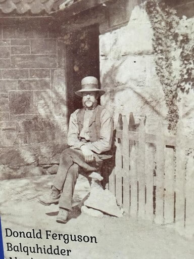 b&w of a man in farm work clothes sitting on his front step, late 1800s