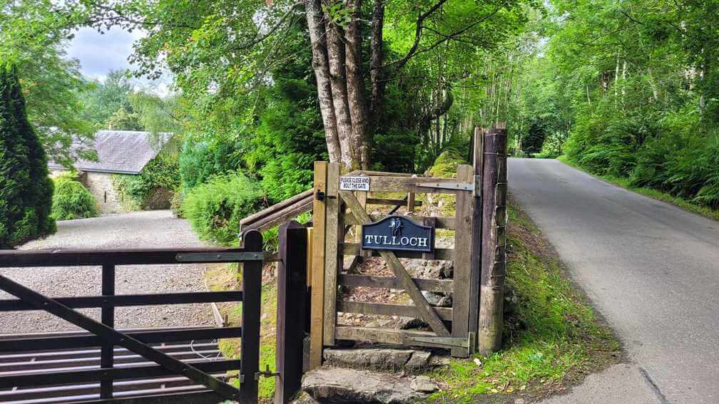 foot gate onto a farmstead property with lush green trees in the background