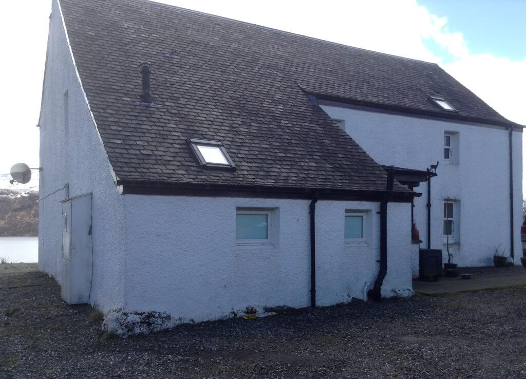 rear view of a renovated 18th century Scottish farmhouse. The old stone walls are whitewashed and the roof is modern.