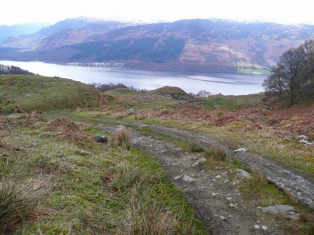 2-track gravel lane looking down a Highland glen to a loch below